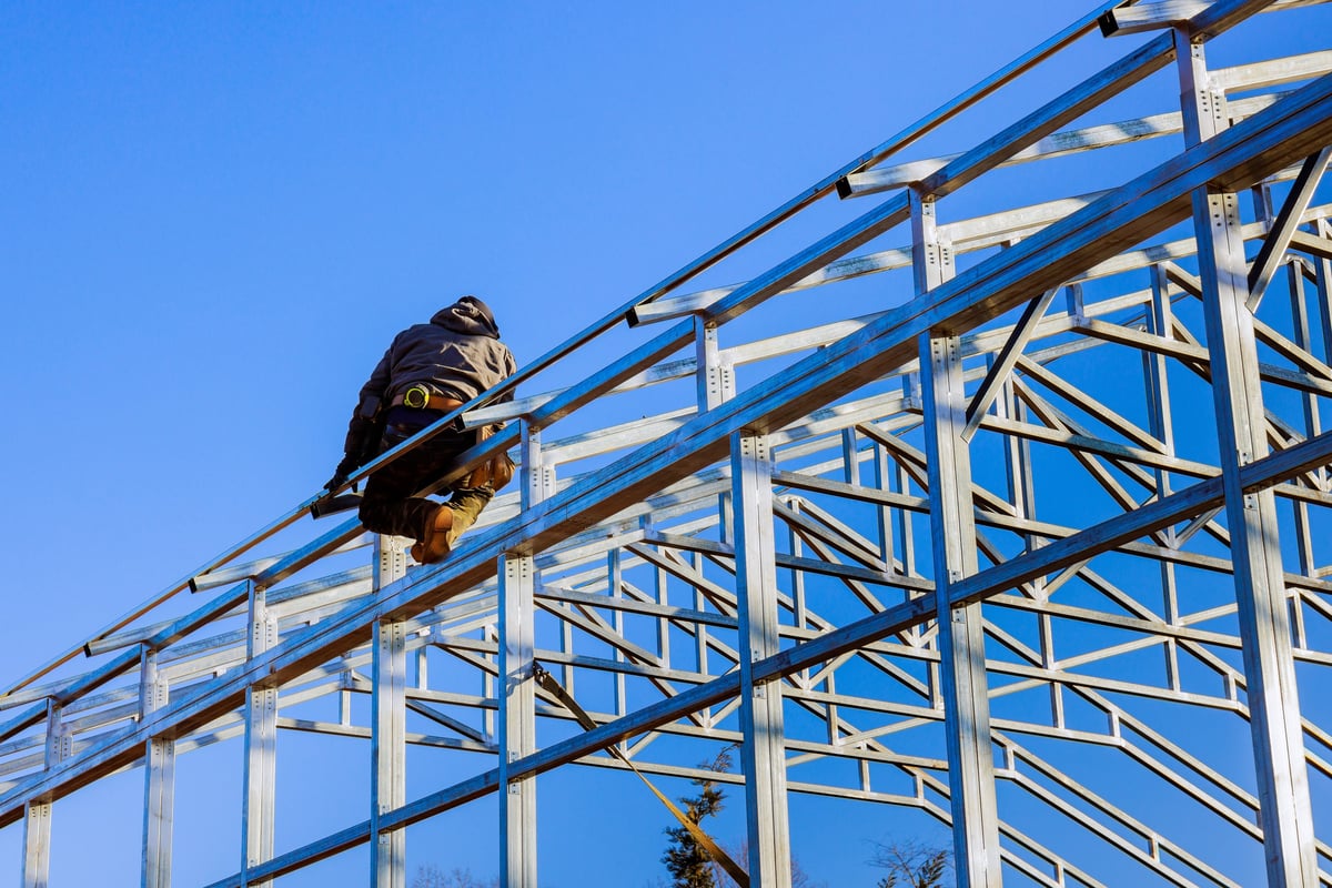 Construction worker assembling greenhouse steel frame structure
